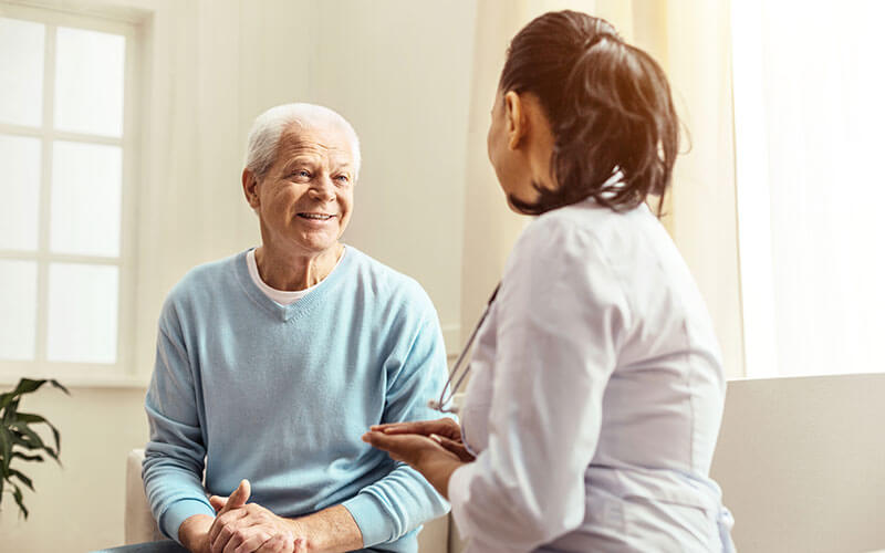 Female doctor speaks with older senior male about his health care needs