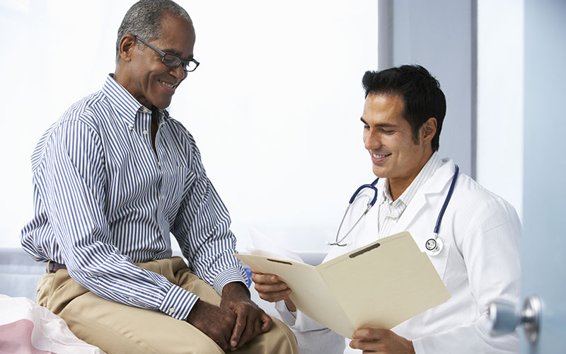 Young male doctor explains health care services to senior adult